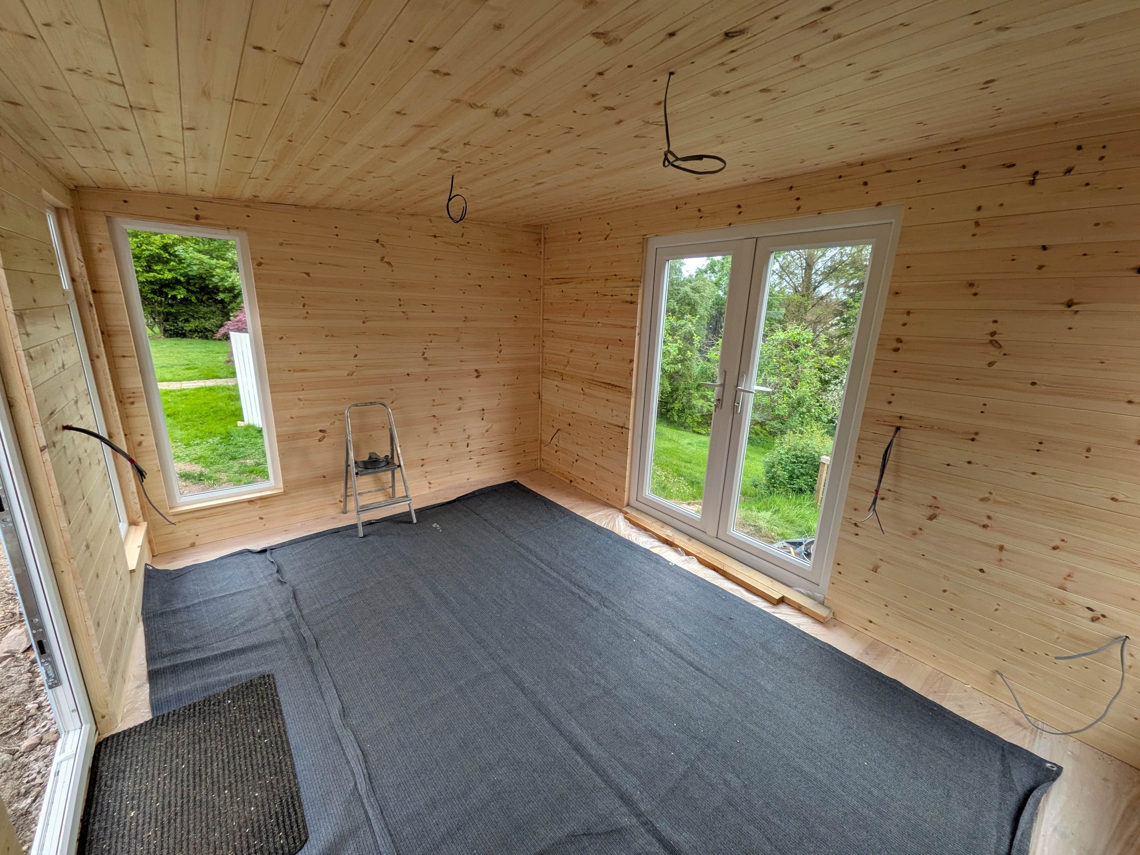 Timber-lined garden room interior with French doors and carpet