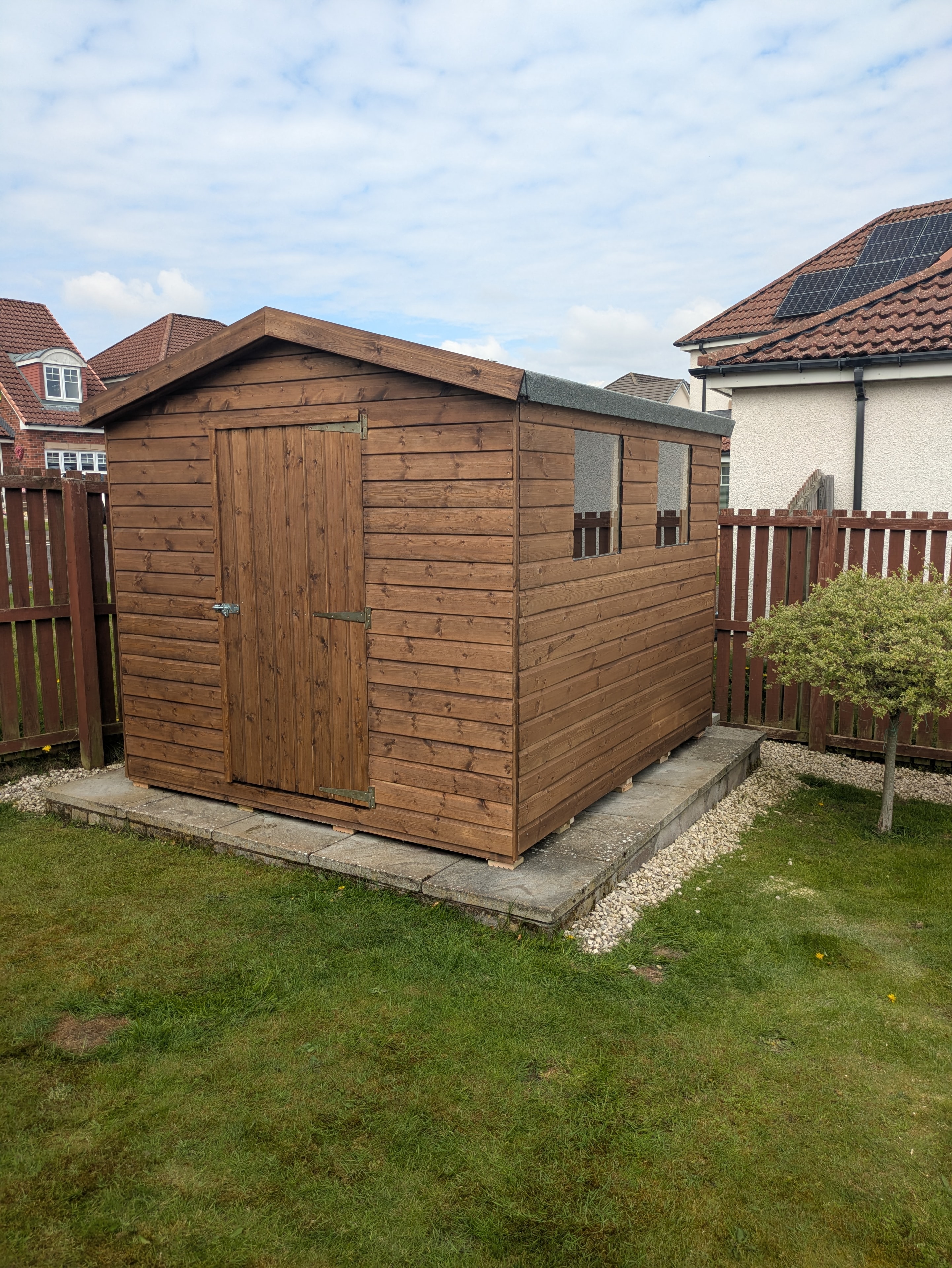 Brown timber garden shed on slab base in residential garden