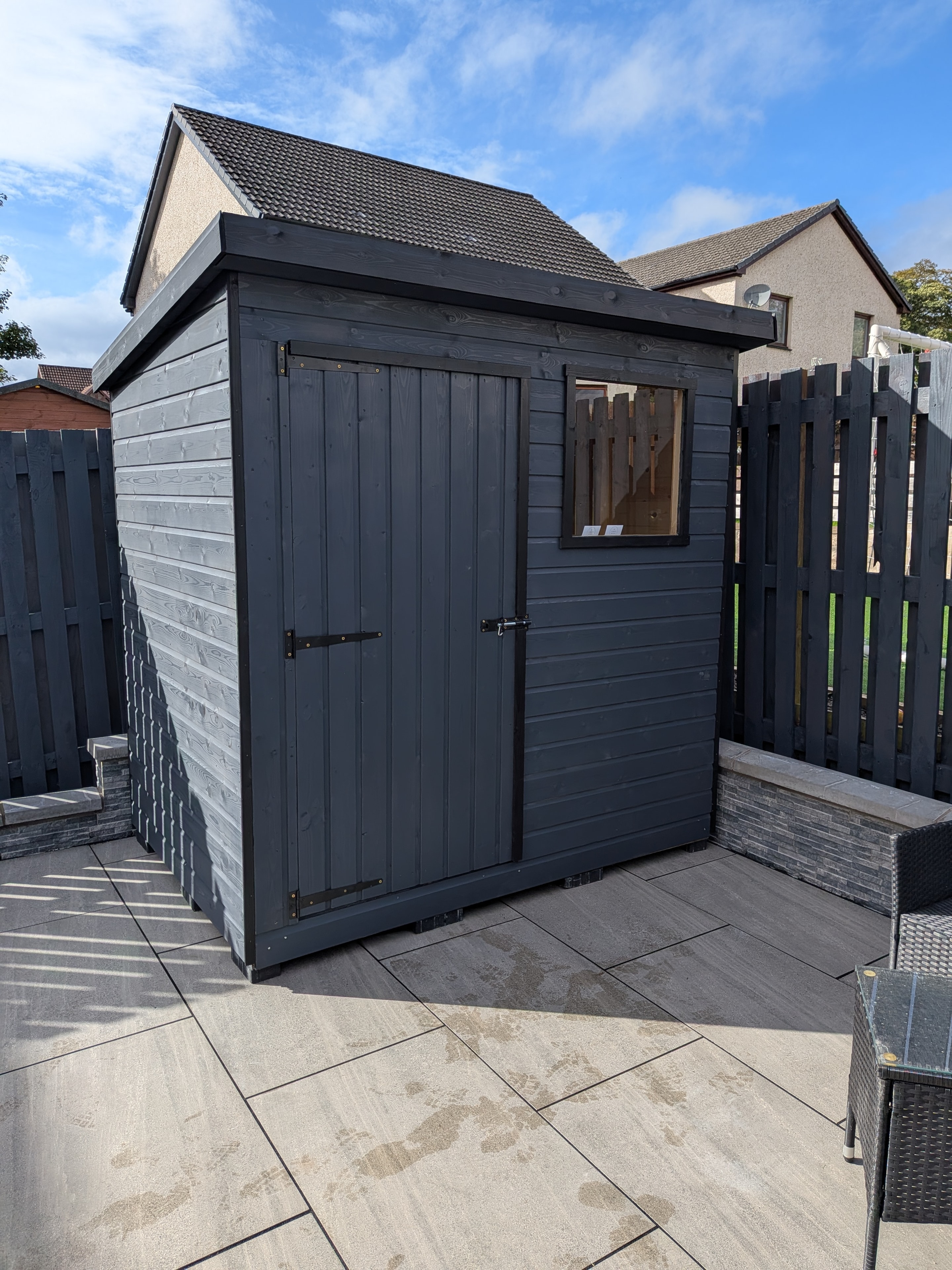 Dark grey painted timber shed on patio with window