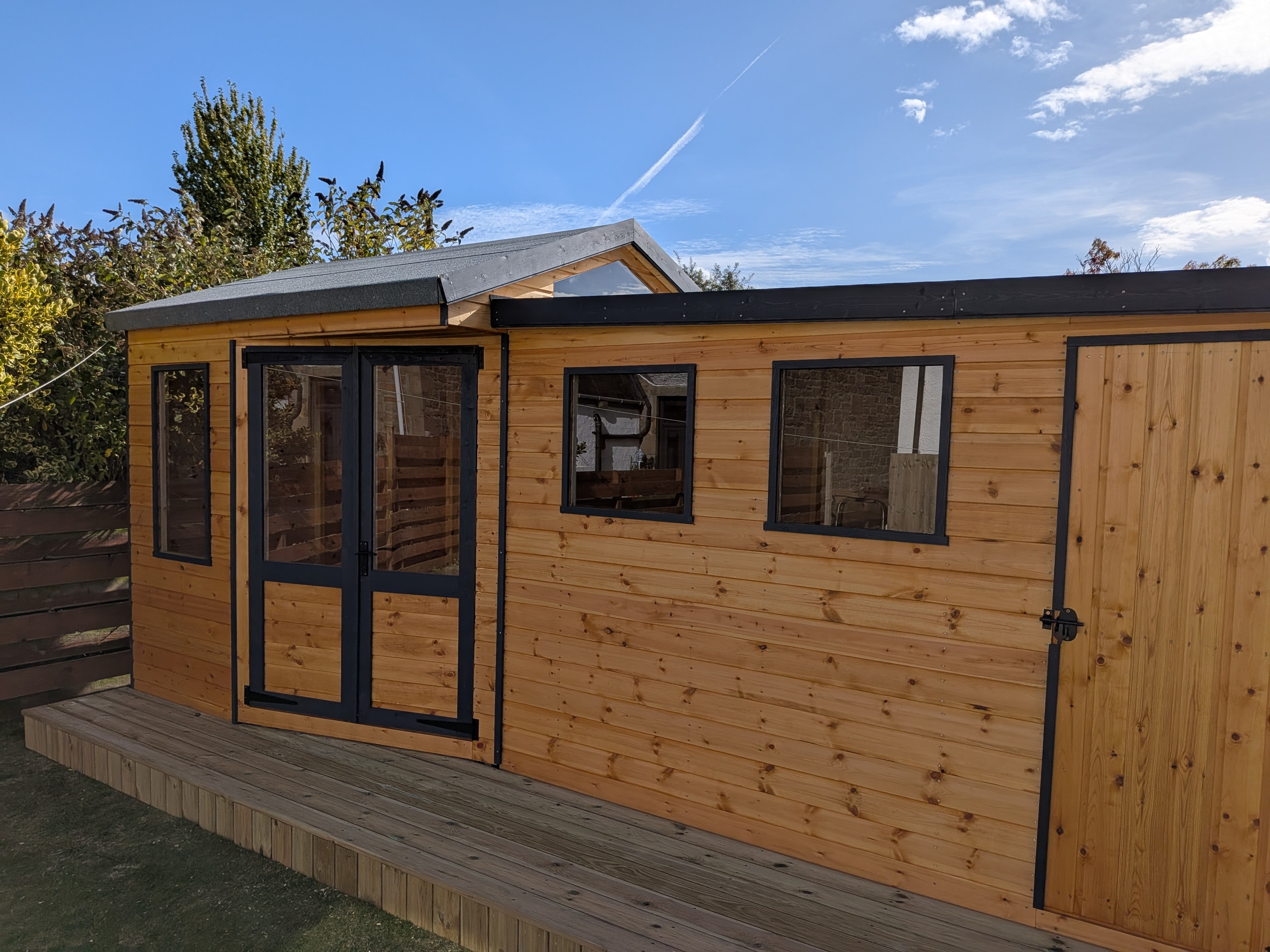 Timber summerhouse with black-framed French doors and decking
