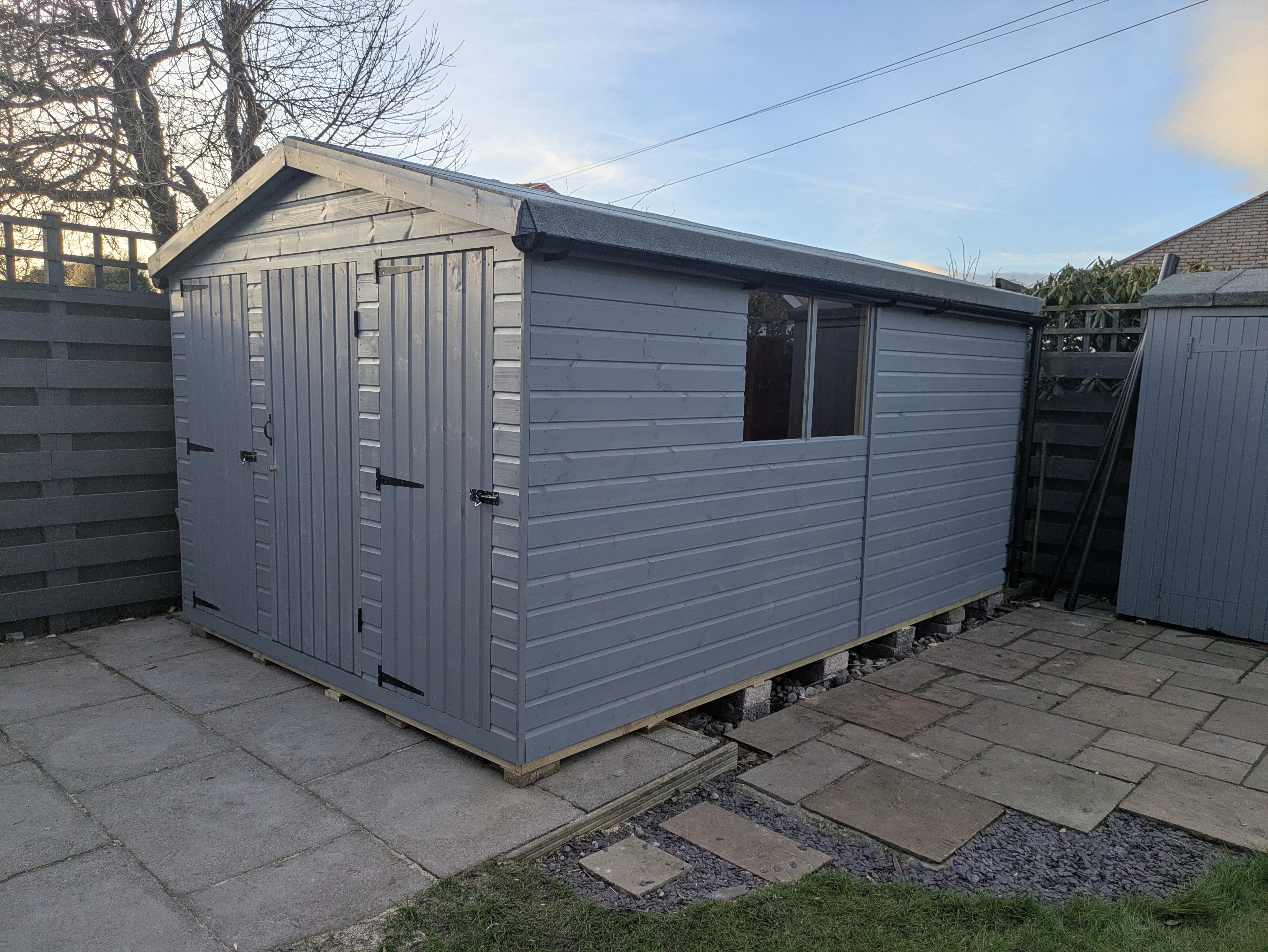 Grey painted timber workshop with double doors on patio